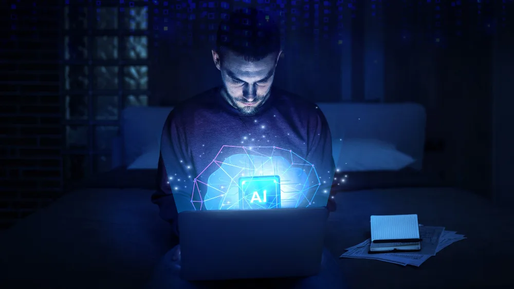  A man is engrossed in his work on a laptop late at night, with a vivid display of AI and network graphics emerging from the screen, symbolizing how Deloitte leverages artificial intelligence to work smarter and more efficiently