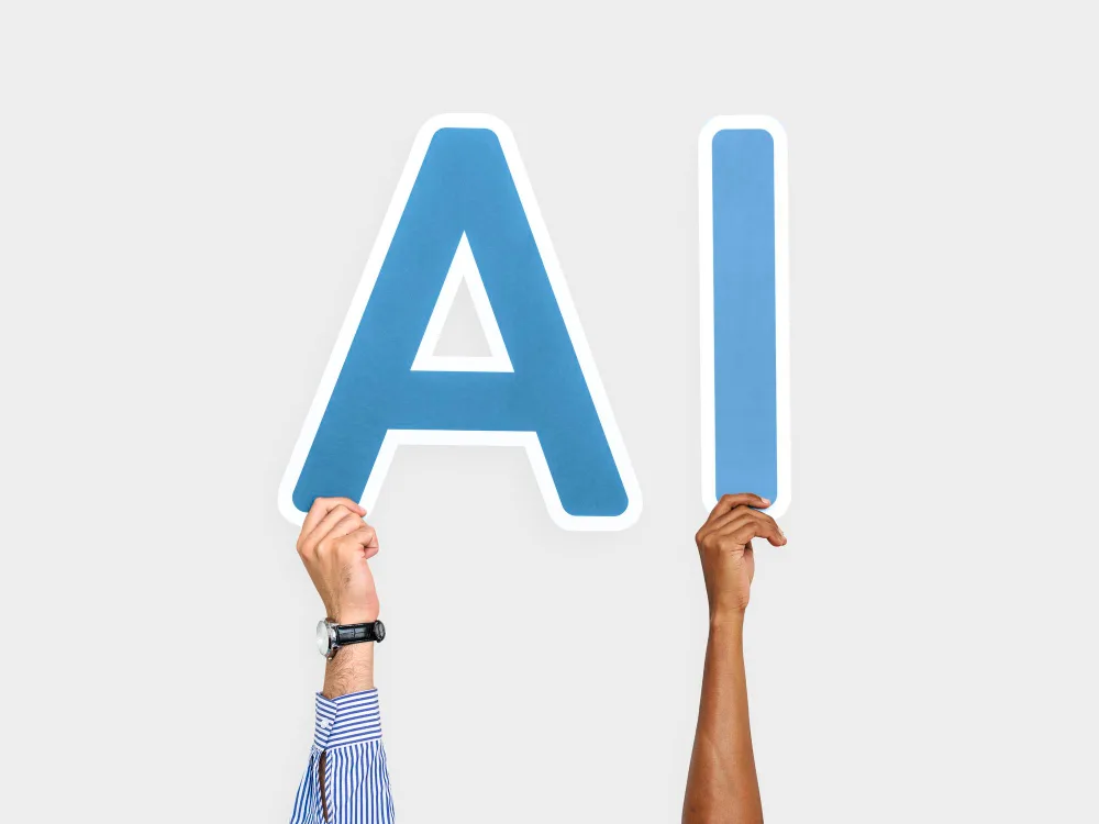 "Two hands holding up large blue letters 'A' and 'I' against a white background, symbolizing the concept of artificial intelligence.