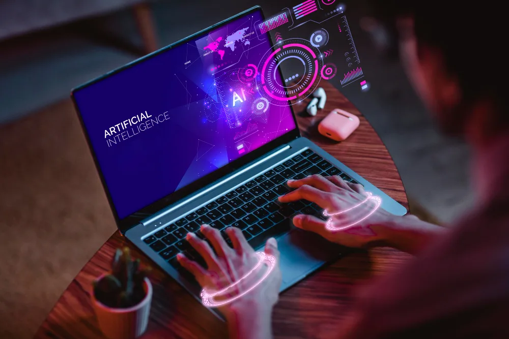 A person using a laptop with a screen displaying vibrant graphics labeled 'Artificial Intelligence', including icons and diagrams related to AI technology. Their hands glow with neon outlines, symbolizing interaction with futuristic technology.