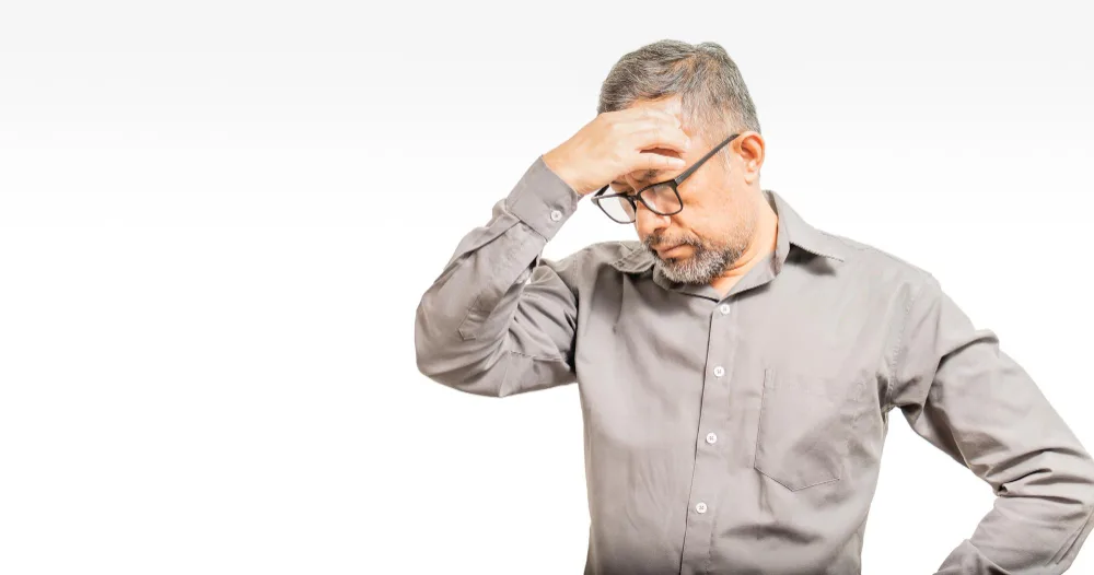  man is holding his head in a gesture of forgetfulness or exhaustion, possibly symbolizing the challenges faced when forgetting advanced techniques in marketing innovation.