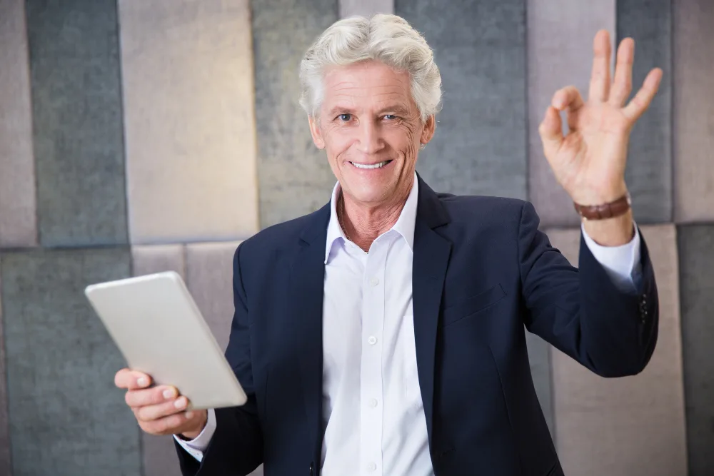 An enthusiastic businessman with a tablet gives a thumbs-up, symbolizing success in getting started with AI for enhancing business processes.